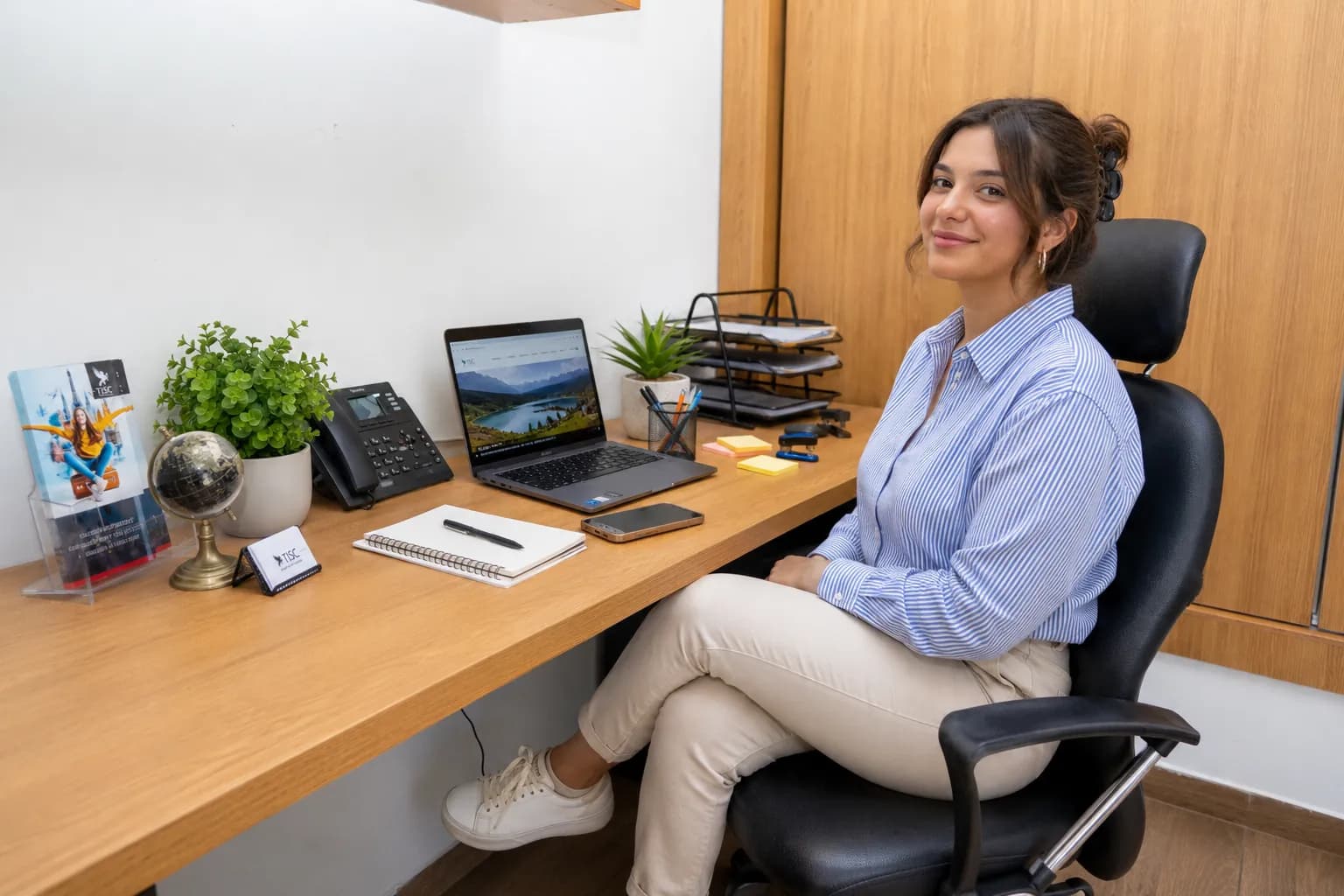 Conseillère TISC à son bureau avec un globe et le site web ouvert sur l'ordinateur
