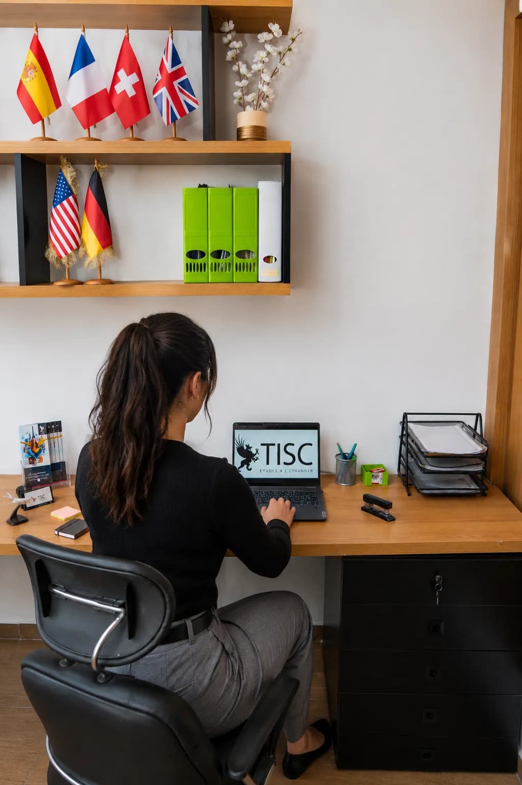 Conseillère TISC au travail sous une étagère de drapeaux de pays
