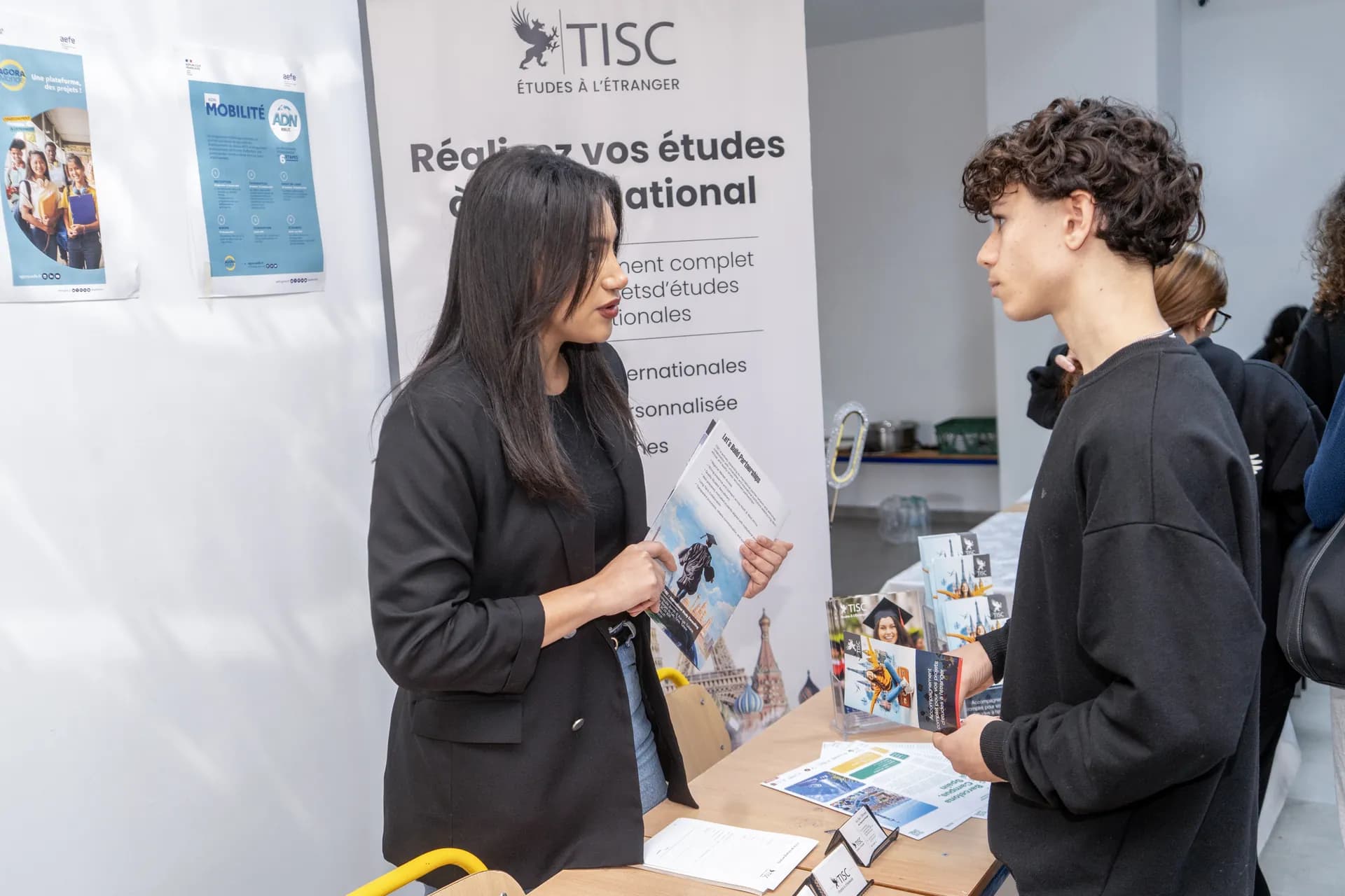 Conseillère TISC présentant une brochure à un étudiant sur un salon